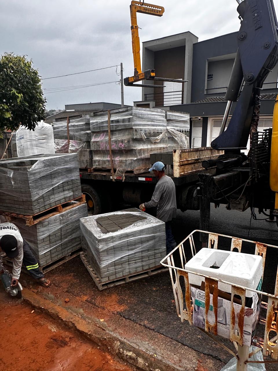 Caminhão Vinic com guindaste descarregando blocos em obra